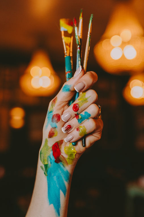 paint stained hand holding paint brushes